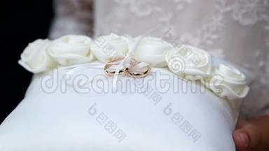戴着结婚戒指的女孩。 白色垫子上的结婚戒指。 垫上两枚金色结婚戒指..